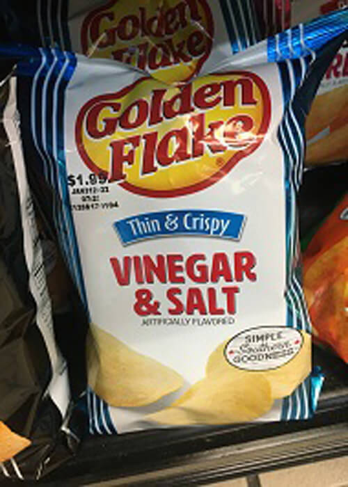 Close up of white and blue bag of Golden Flake potato chips, vinegar and salt flavor.