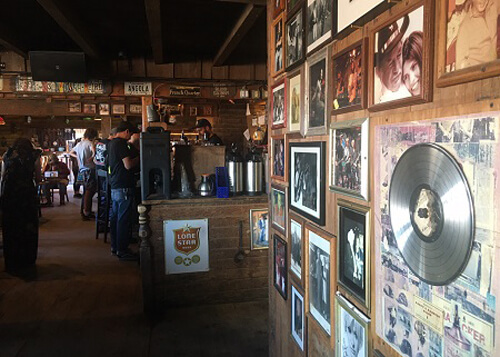 Inside of Pappy and Harriet's restaurant, with a photo wall at right with silver record in display case hanging next to photos.