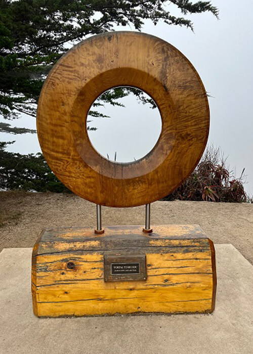 Three-foot wooden donut shaped art monument structure on a stand, called the "portal to Big Sur." 