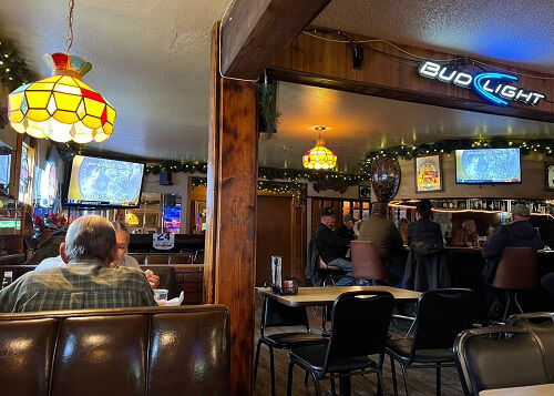 Inside a woodsy restaurant bar with yellow lamps and neon beer signs