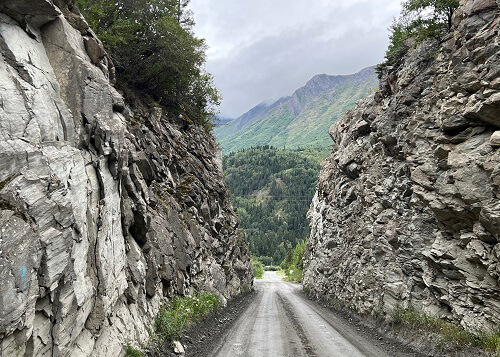 Narrow dirt and rock road cutting through a rocky hill