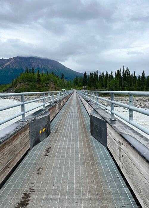 Looking across Kennicott River on walkway bridge, cloudy sky above