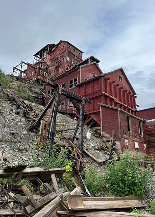 Looking up hill at old red processing mine, cloudy sky above