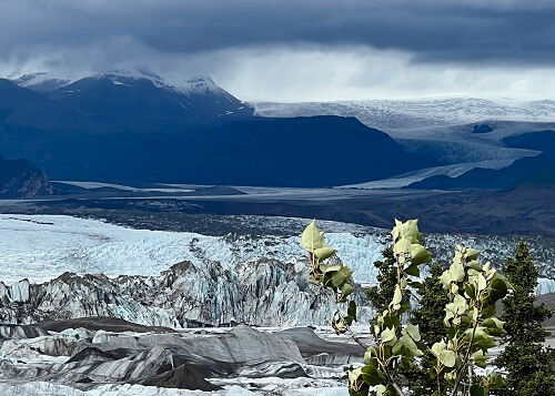 Snow covered mountains and ice waterfall in the distance, glacier at foreground 