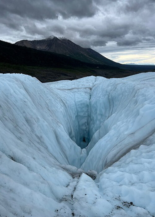 Glacier with hole going down, mountain in background