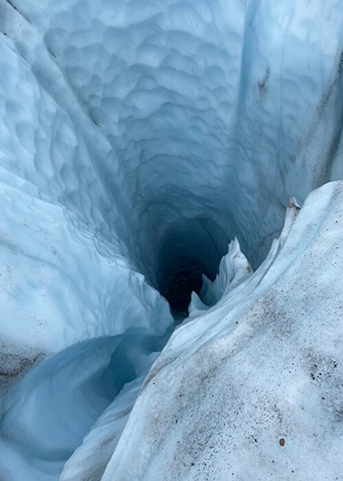 Looking down a dark hole in a glacier