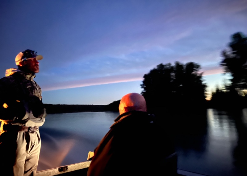 Two fisherman on a boat in river at sunrise