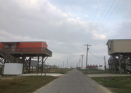 Street with a house on each side, both high up on flood stilts.