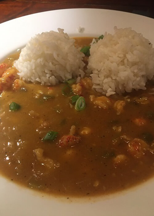 Two scoops of rice on crawfish étouffée dish. 