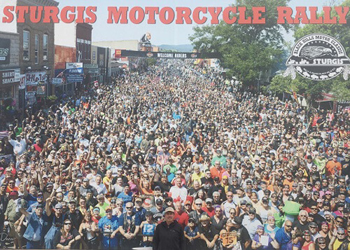 Picture of wall sized photo of Sturgis bike rally with thousands of people crowded in the street.