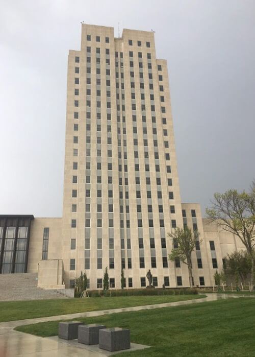 24-story state capitol building of North Dakota, light tan colored and block style with no trim.  Grey sky behind building.