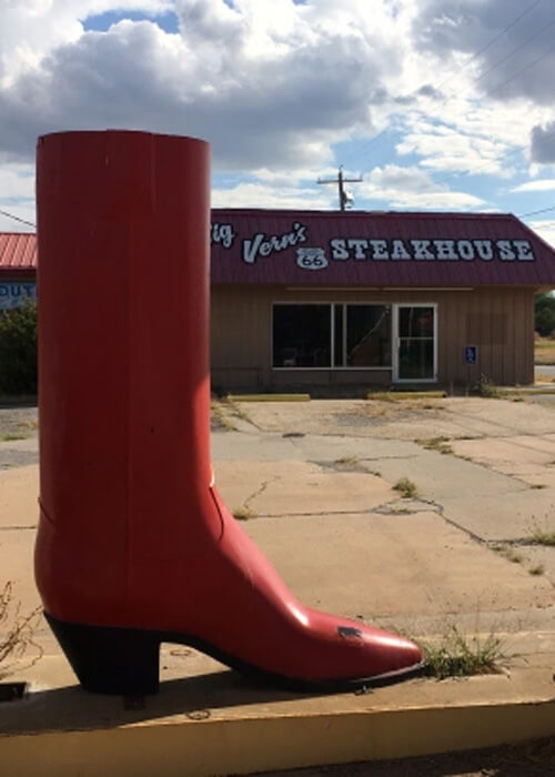 Life-sized red boot at left and restaurant to the right saying "Von's steakhouse."  Blue sky above with puffy clouds.