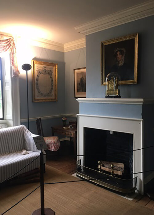 A social room inside Monticello, with light blue painted walls, some paintings and a fireplace.