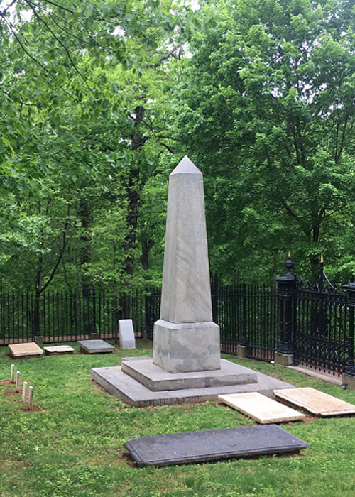 Thomas Jefferson's tomb, a tall four-sided pyramid-type structure made of marble. Green trees in background.