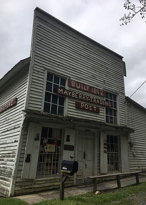 1892 wooden building covered in clapboard, two stories high. Sign says Mayberry Trading Post.