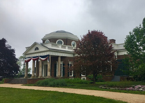 Thomas Jefferson's Monticello home, with round dome above the single-story colonial-style brick building. Grey overcast skies above.