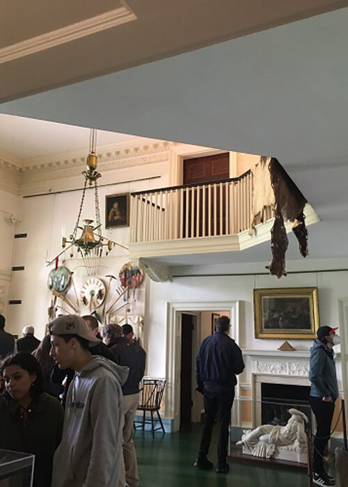 Monticello's entry room, with Indian artifacts on the walls and tourists looking at the displays.