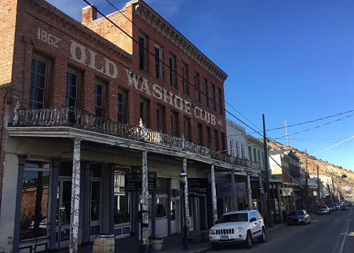 Row of old west looking brick and wooden buildings in downtown Virginia City, largest building on left is three-story brick building with painted-on sign saying "1862 Old Washoe Club."