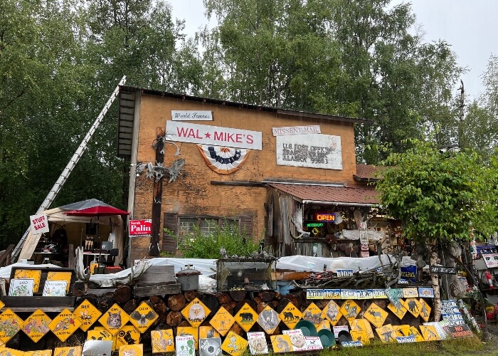 Rickety storefront with various odds and ends in front, sign that says "Was Mike's"