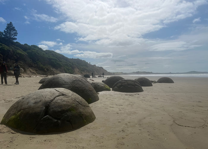 Groups of large, oversized boulders embedded in hard sand at a beach.