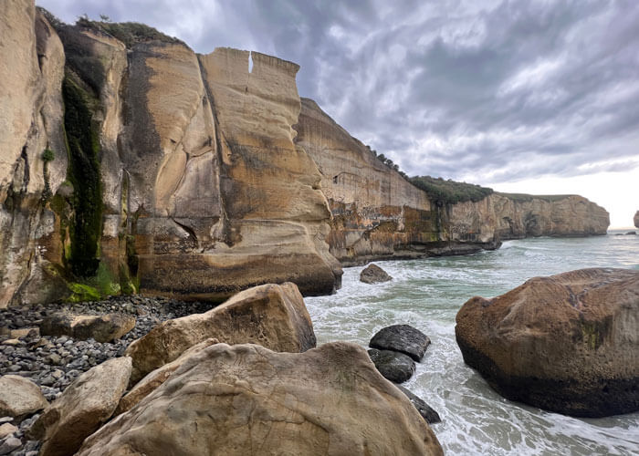 Brown cliffsides along the water at Tunnel Beach.