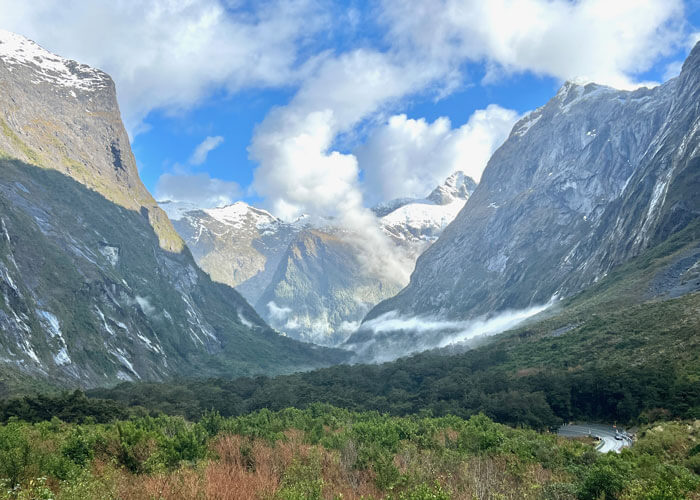 Landscape view of Fiordland National Park, with snow dotting some of the mountains that surround the tree-filled valleys.