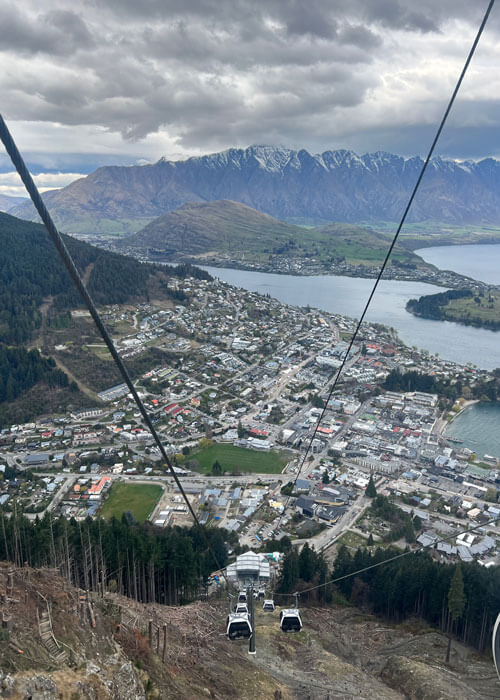 View from a gondola high up on a mountainside looking down at the city of Queenstown, New Zealand.